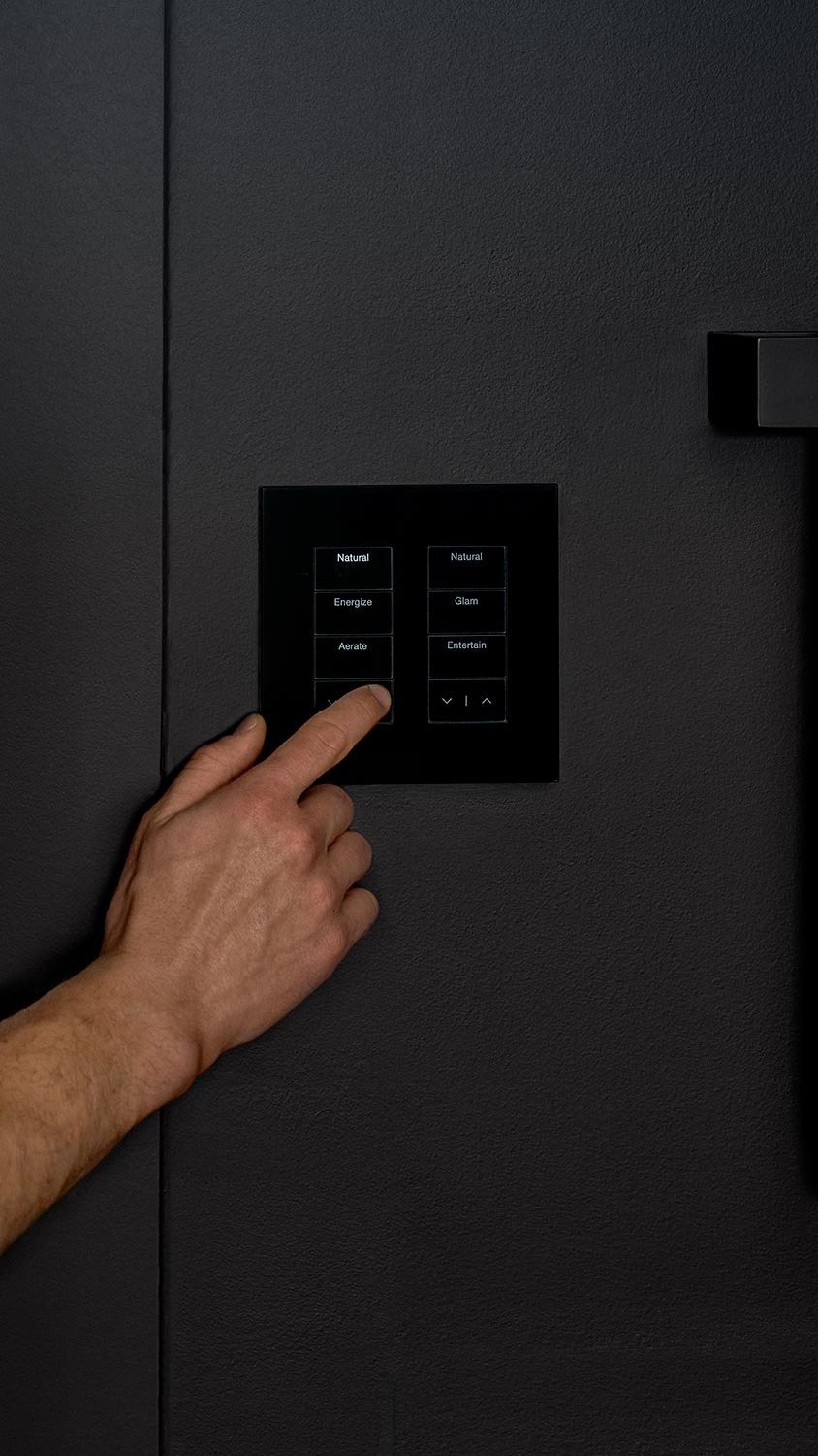 Hand pressing a lighting control panel labeled Lutron